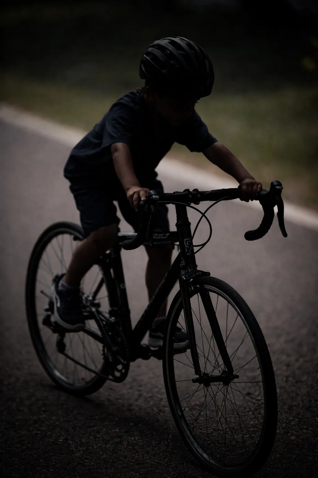 Enfant sur un vélo trop grand dans une ambiance sombre